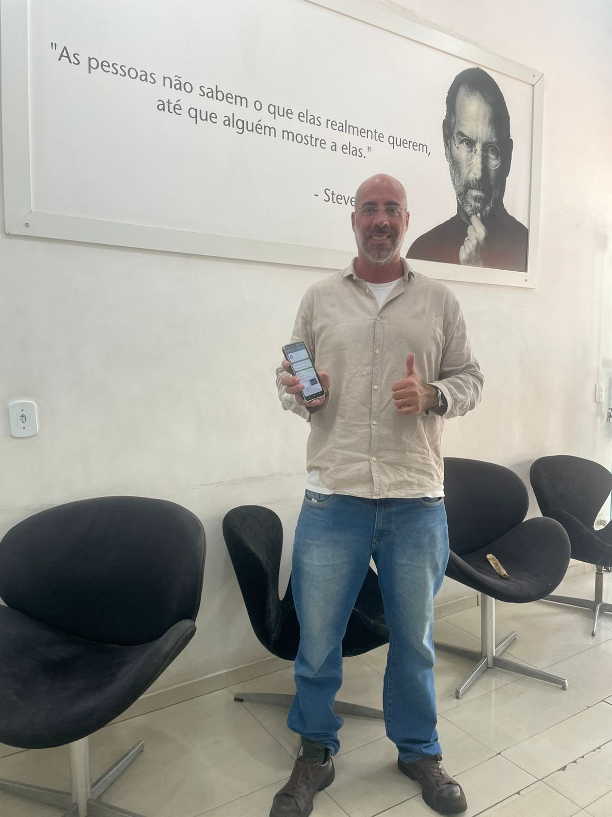 Cliente de camisa bege fazendo positivo com o celular na loja iPlanet