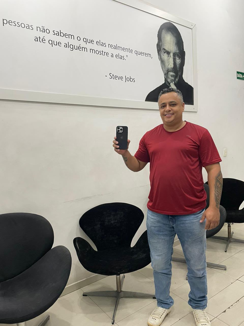 Cliente de camiseta vermelha com o iPhone na sala de espera da iPlanet