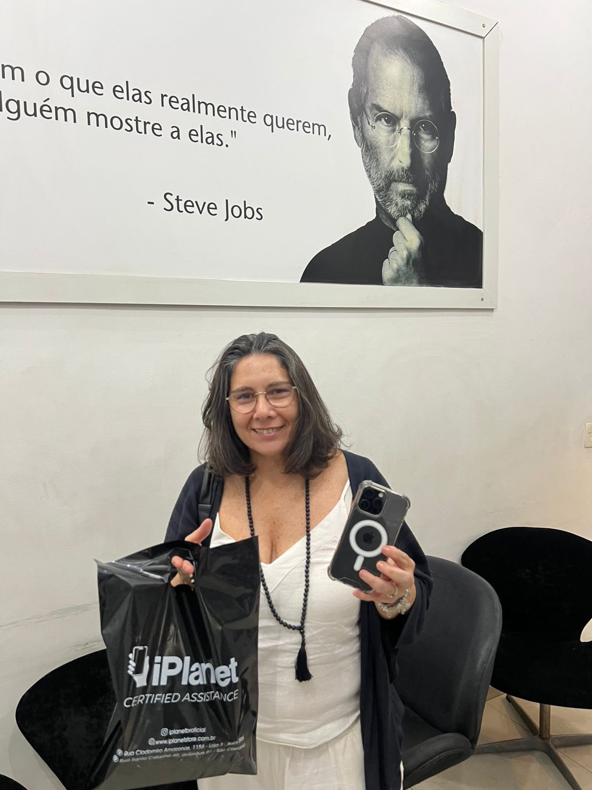 Cliente com a sacola da iPlanet e o celular na sala de espera da loja