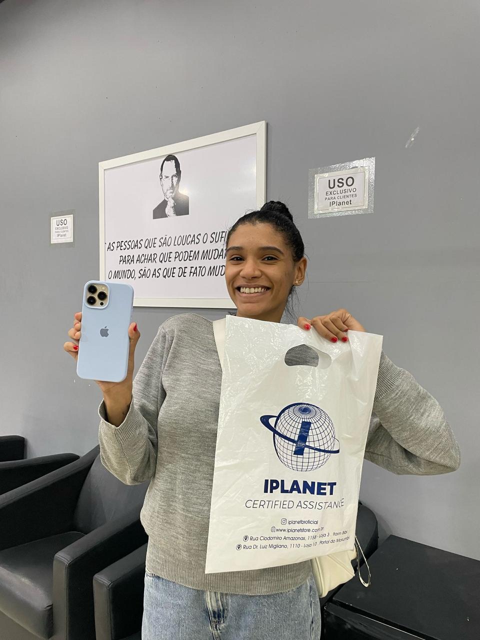 Cliente sorrindo com o iPhone azul e a sacola da iPlanet em São Caetano do Sul